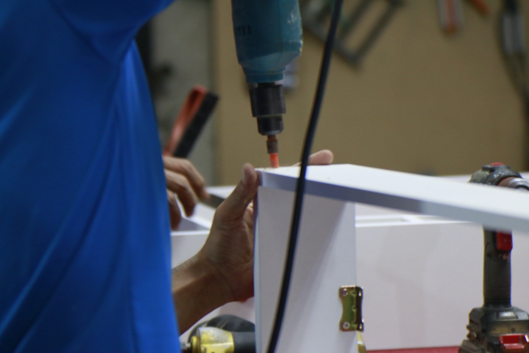 A craftsman hand-assembling a HAÜS piece with a drill, screws only, no glue