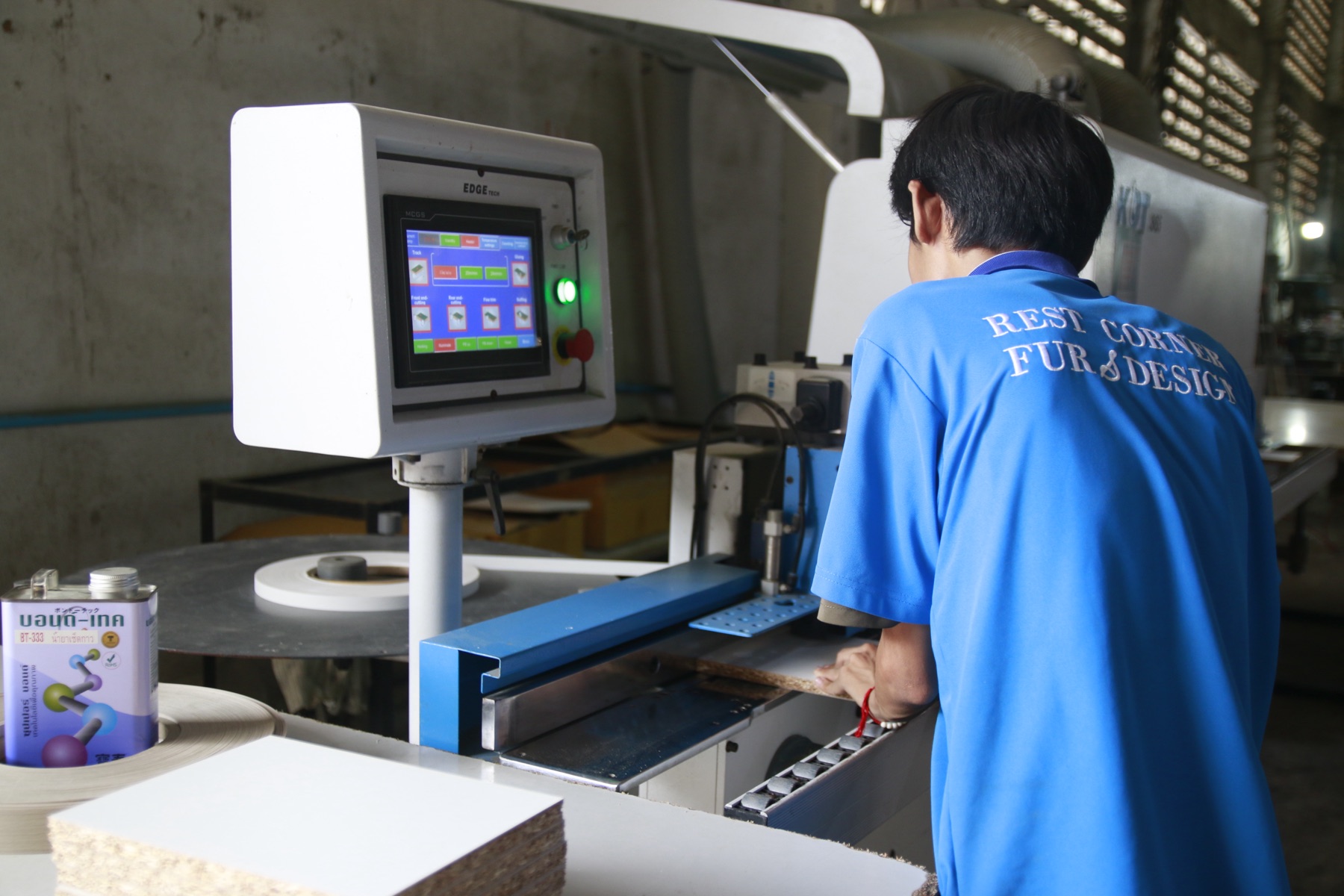 A craftsman finishing panel edges on an edge-banding machine