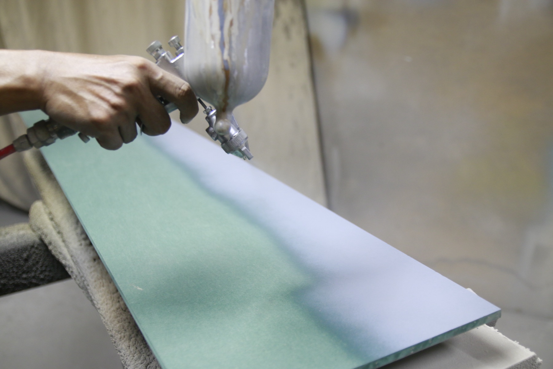 A craftsman spray-painting the edge of a HAÜS panel by hand